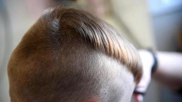 coupe de cheveux pour enfants dans le salon. coiffure de petit garçon. coiffure pour enfants. coiffeur faisant une coiffure élégante pour petit garçon video