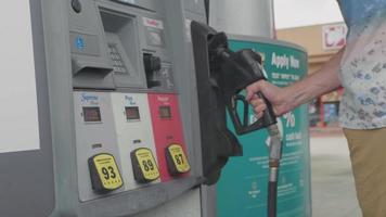 man in tankstation plaatsen van een mondstuk in brandstof dispenser video