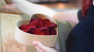 Valentine Gift. Young Girl opening heart gift box with rose petals video