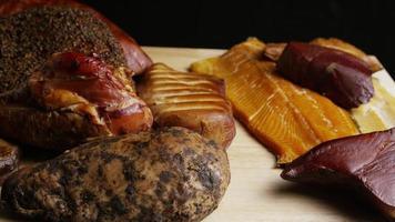 Foto giratoria de una variedad de deliciosas carnes ahumadas premium sobre una tabla de cortar de madera - comida 055 video