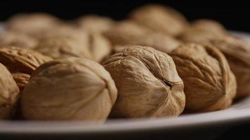 Cinematic, rotating shot of walnuts in their shells on a white surface - WALNUTS 034 video