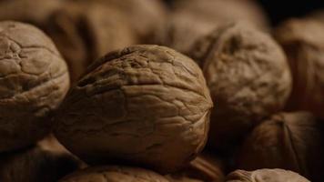 Toma cinematográfica giratoria de nueces con cáscara sobre una superficie blanca - nueces 090 video