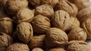 Cinematic, rotating shot of walnuts in their shells on a white surface - WALNUTS 072 video