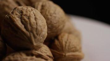 Cinematic, rotating shot of walnuts in their shells on a white surface - WALNUTS 089 video