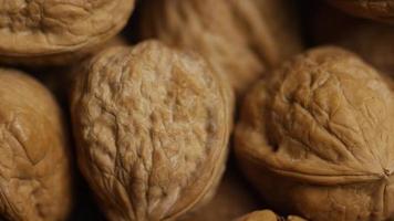 Cinematic, rotating shot of walnuts in their shells on a white surface - WALNUTS 059 video