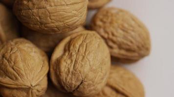 Cinematic, rotating shot of walnuts in their shells on a white surface - WALNUTS 057 video