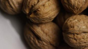Cinematic, rotating shot of walnuts in their shells on a white surface - WALNUTS 058 video
