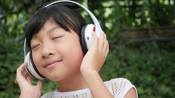 Little girl listens to music from headphone and good feeling video