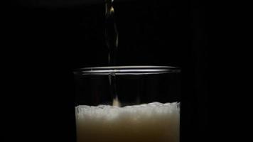 Beer is pouring into glass with foam sliding down side of beer glass video