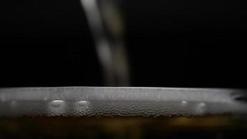 Beer is pouring into glass with foam sliding down side of beer glass video