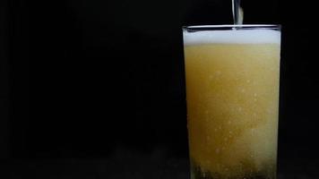 Beer is pouring into glass with foam sliding down side of beer glass video