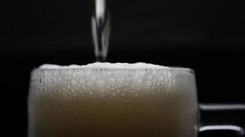 Beer is pouring into glass with foam sliding down side of beer glass video