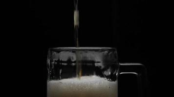 Beer is pouring into glass with foam sliding down side of beer glass video