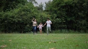 Slow motion of parents with daughter running enjoy in the park 