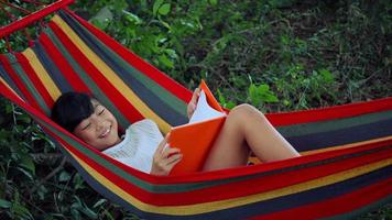 Little girl chilling on hammock and reading a book story video