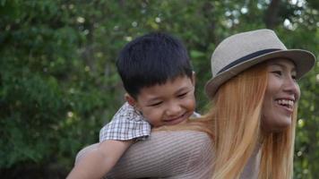 Asian boy on a piggy back ride with his mother in slow motion video