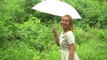 Woman walking hand holding white umbrella at the park  video