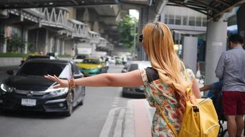 mulher viajante acenando para um carro táxi na cidade