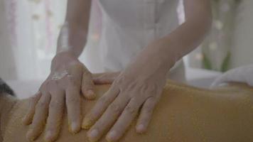 Joven recibiendo un tratamiento de exfoliación con sal en el spa aromaterapia video