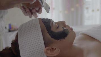 Young beautiful woman receives charcoal spa therapy  video