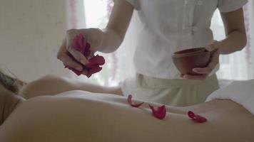 jovem mulher bonita no salão de massagem spa. tratamento de relaxamento com cheiro de flores rosas. video