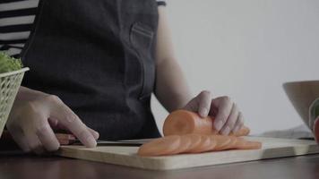 Cerca de la mujer jefe haciendo ensalada de alimentos saludables y picar zanahoria en la tabla de cortar en la cocina. video