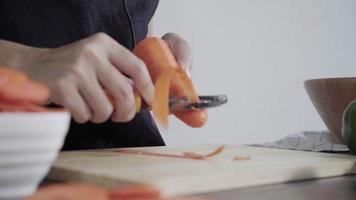 Close up del capo donna che fa insalata cibo sano e tritare la carota sul tagliere in cucina. video