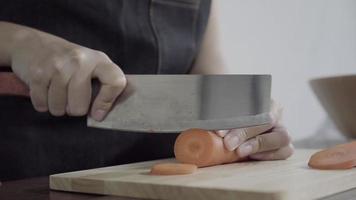 Close up del capo donna che fa insalata cibo sano e tritare la carota sul tagliere in cucina. video