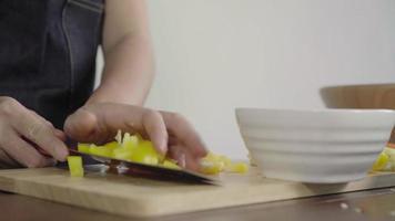 Close up del capo donna che fa insalata cibo sano e tritare il peperone sul tagliere. video