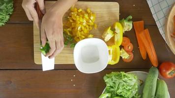 Vista superior de la mujer jefe haciendo ensalada de comida sana y picar pimiento en la tabla de cortar en la cocina. video