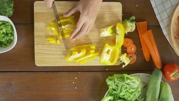 Draufsicht des Frauenchefs, der gesundes Essen des Salats macht und Paprika auf Schneidebrett in der Küche hackt. video