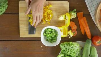Draufsicht des Frauenchefs, der gesundes Essen des Salats macht und Paprika auf Schneidebrett in der Küche hackt. video