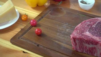 Cerca del chef gourmet o cocinera condimentando trozos frescos de carne de res con sal marina y pimientos picantes molidos. video