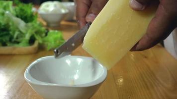 câmera lenta - close-up vista da mão do chef picar queijo na tábua de madeira. processo de cozimento. video