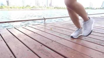 câmera lenta - jovem mulher asiática correndo na calçada pela manhã. mulher asiática jovem esporte correndo no parque. aptidão executando esportes pessoas e conceito de estilo de vida saudável. video