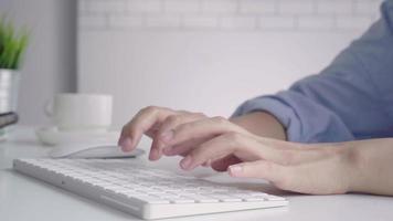 Beautiful young smiling Asian woman working on laptop while at home in office work space. Businesswoman working from home via portable computer writing on keyboard. Enjoying time at home. video