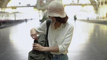 reiziger backpacker aziatische vrouw reizen in bangkok, thailand. gelukkige jonge vrouwelijke richting en kijken op locatiekaart op treinstation voor reizen. video