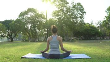 ung asiatisk kvinnayoga utomhus håller sig lugn och mediterar medan de tränar yoga för att utforska den inre freden. yoga och meditation har goda fördelar för hälsan. yogasport och hälsosam livsstilskoncept. video