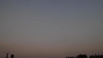 Boy running in a field with a toy wooden airplane in his hands at sunset video