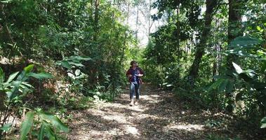 junger Mann, der im tropischen Dschungel mit Rucksack wandert.