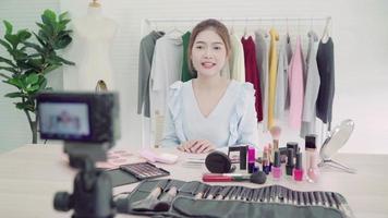 blogueuse beauté présente des cosmétiques de beauté assis devant la caméra pour enregistrer une vidéo. belle femme asiatique utilise des produits cosmétiques tout en examinant le tutoriel de maquillage diffusé une vidéo en direct sur le réseau social par internet video