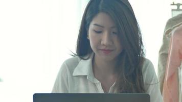 Beautiful young smiling woman working on laptop while enjoying drinking warm coffee sitting in a living room at home.  video