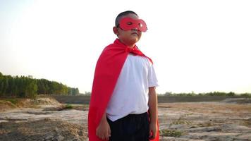 Silhouette of a boy having fun dressed as a superhero running in a field video