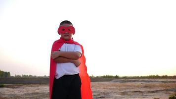 silueta de un niño divirtiéndose vestido como un superhéroe corriendo en un campo