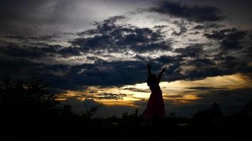 silhouette di una bambina felice che cammina con il sole al tramonto sullo sfondo video