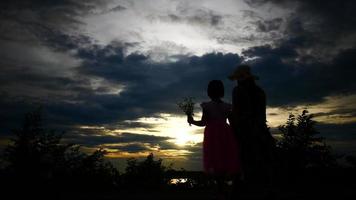 silhuetas de mãe e filha se divertindo com o pôr do sol ao fundo video