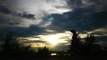 Silhouette of woman raising her hands with the setting sun in the background video