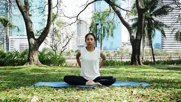 ung asiatisk kvinnayoga utomhus håller sig lugn och mediterar medan de tränar yoga för att utforska den inre freden.