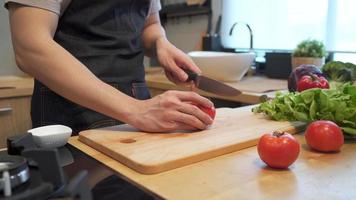 manos de hombre asiático cortando tomate en tabla de cortar. video