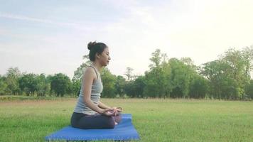 jonge Aziatische vrouw yoga buitenshuis blijf kalm en mediteert tijdens het beoefenen van yoga om de innerlijke rust te verkennen. video